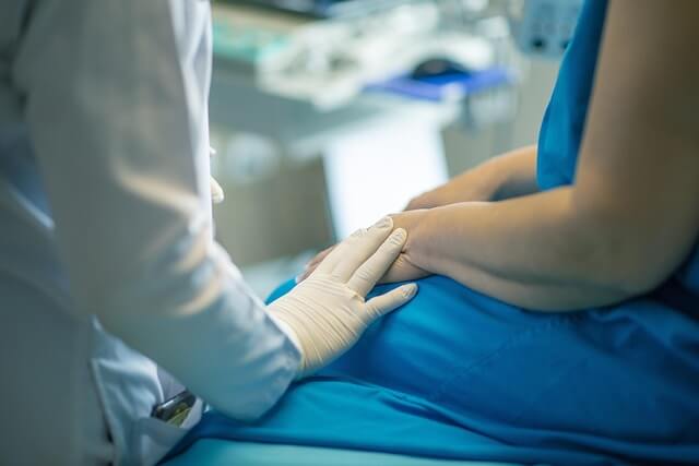 uma mulher com roupa de hospital e uma média com luvas brancas