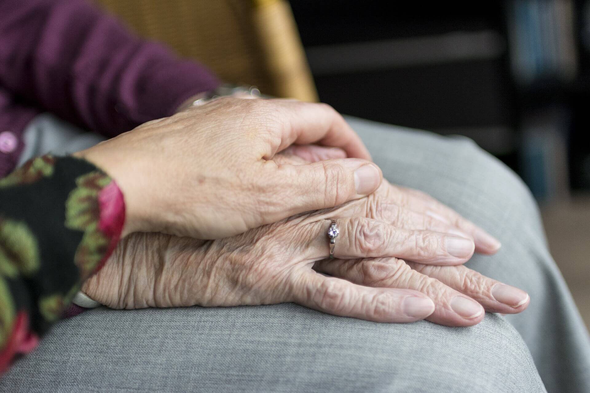 uma mao segurando mãos de uma idosa, provavelmente mãe e filha